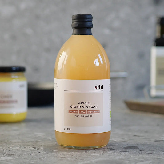 STHL organic raw unfiltered apple cider vinegar with the mother in a 500ml bottle on a kitchen countertop.