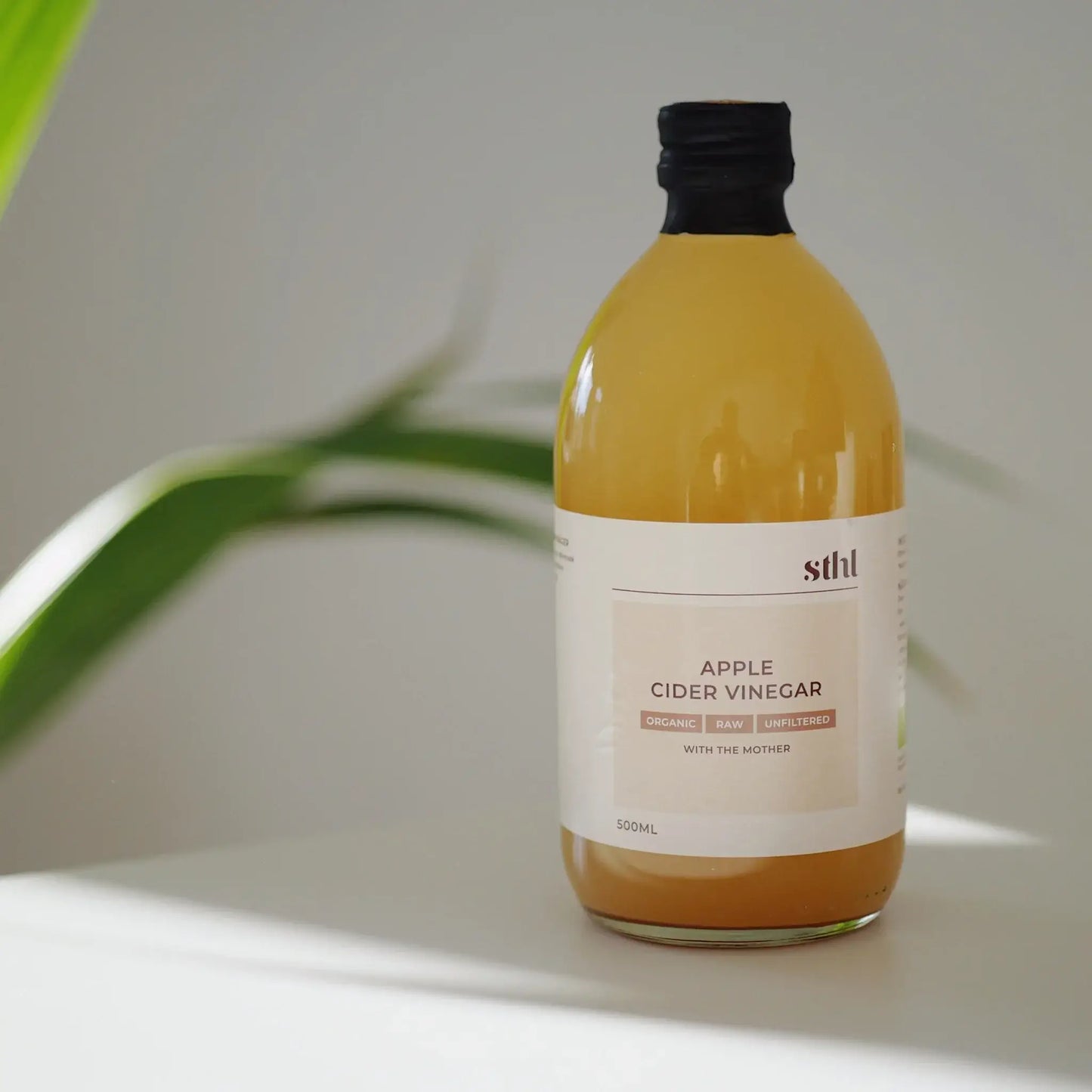 STHL organic raw unfiltered apple cider vinegar bottle with the mother, 500ml, placed on a soft blurred background.