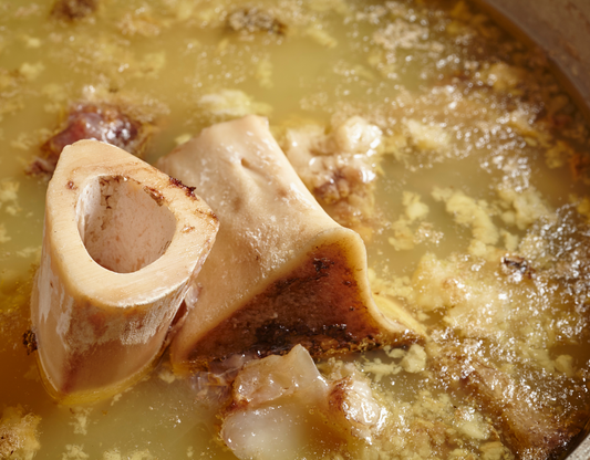 Close-up of bone broth simmering with bone pieces and fat, highlighting its nutritious benefits.